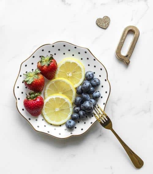 strawberry, lemon, and berries on a plate